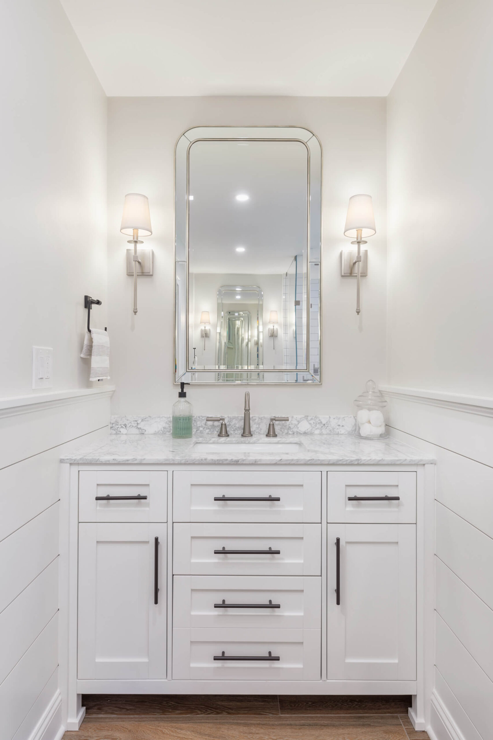 custom vanity built between walls, mirror, decorative sconces on either side of mirror