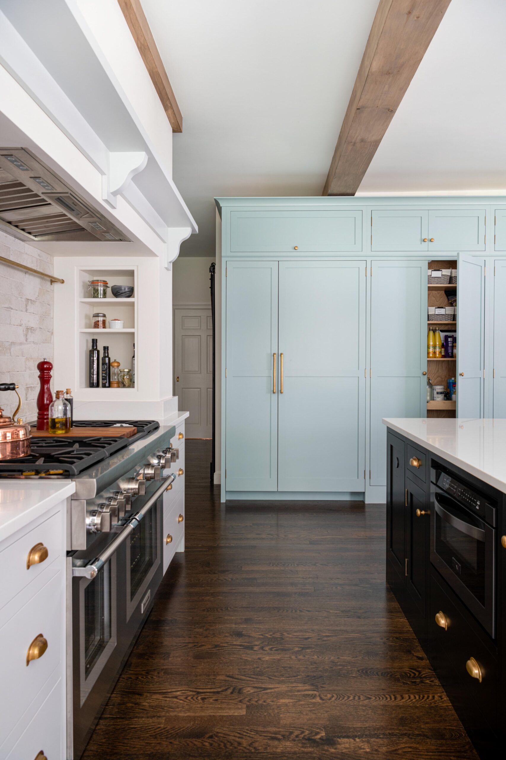 Kitchen with black and white cabinets and wooden floor. It has a huge light blue cabinets that functions as the pantry.