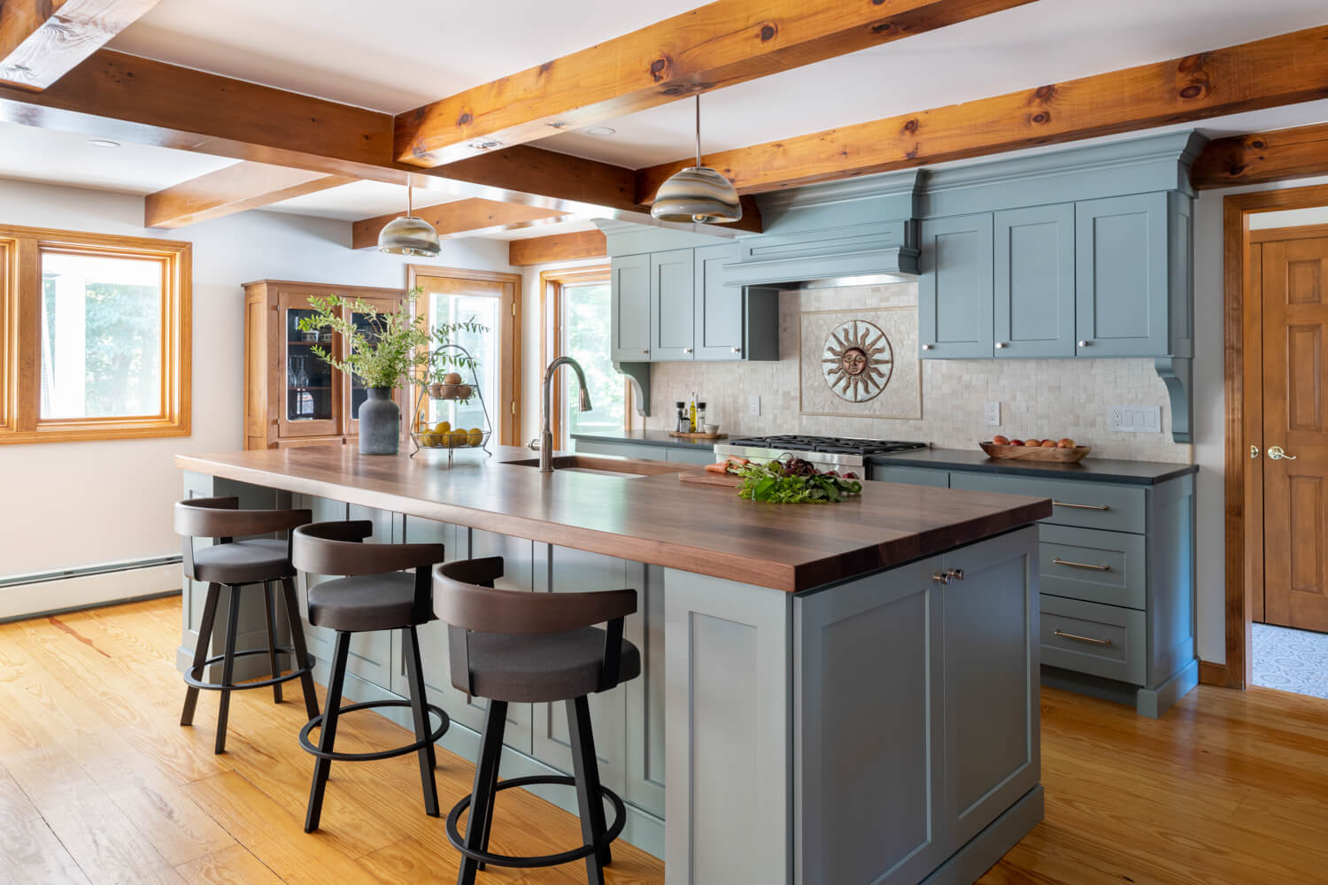 walnut island countertop, blue painted cabinetry, exposed wooden beams