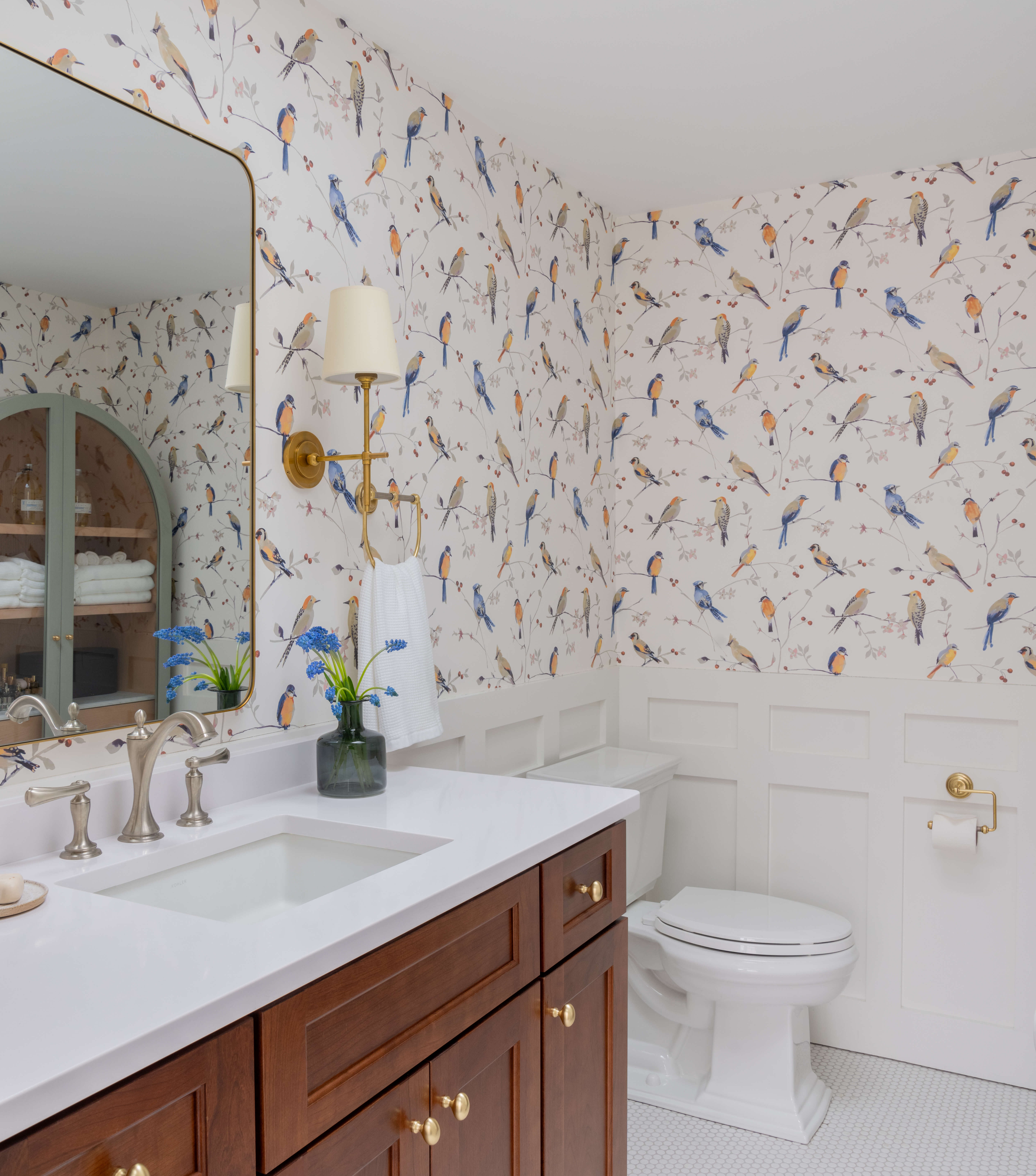 bathroom with bird wallpaper, skylight, sconces, vanity and mirror