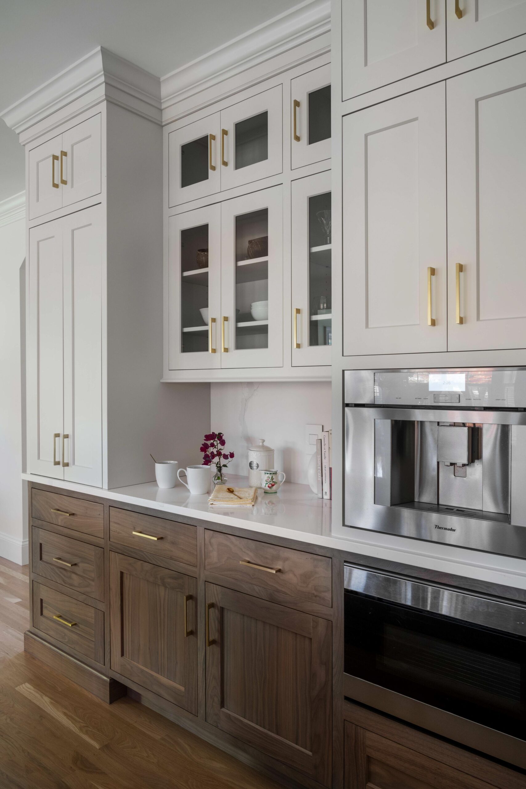 White and wooden style kitchen cabinets. This kitchen also has a glass-front style top cabinets.