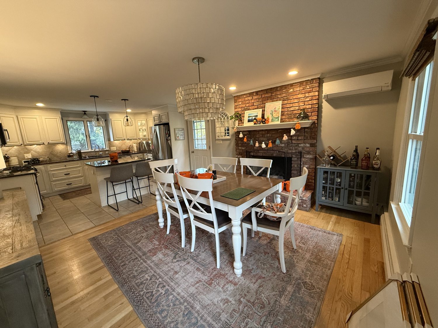 Original kitchen with white cabinets, a tile floor and a dining table by the brick fireplace