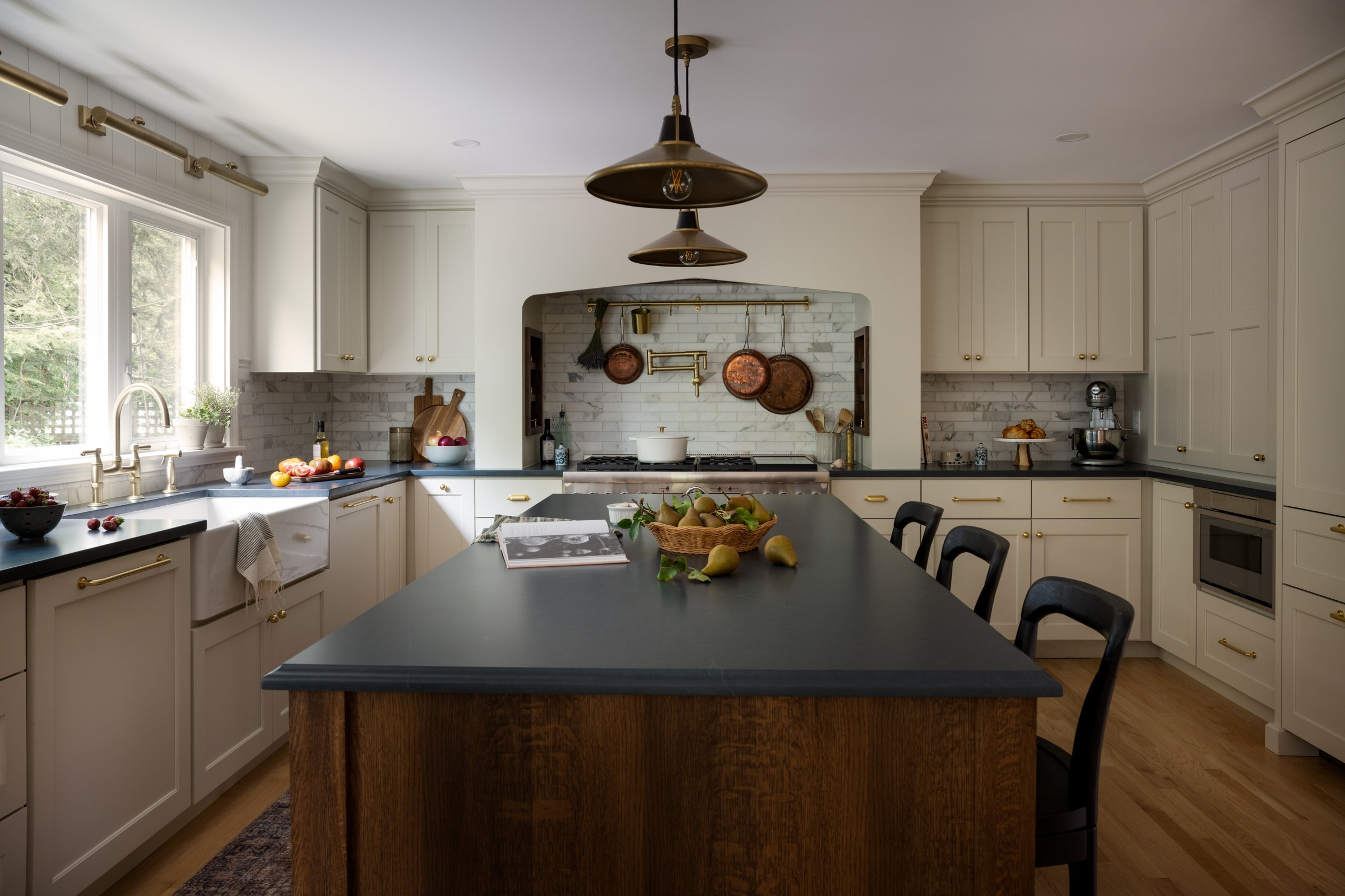 Kitchen with a quartersawn white oak island under two brass pendants, looking toward the range alcove