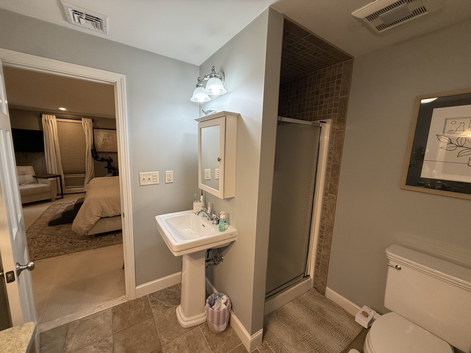 Original primary bathroom with a pedestal sink, a tiled shower stall and a door through to the bedroom