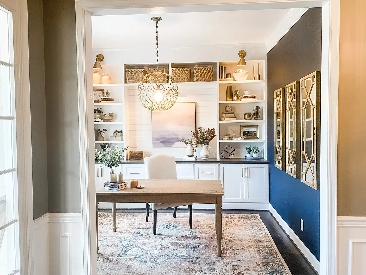 home office with white built-ins, black feature wall, large round light fixture, colorful rug