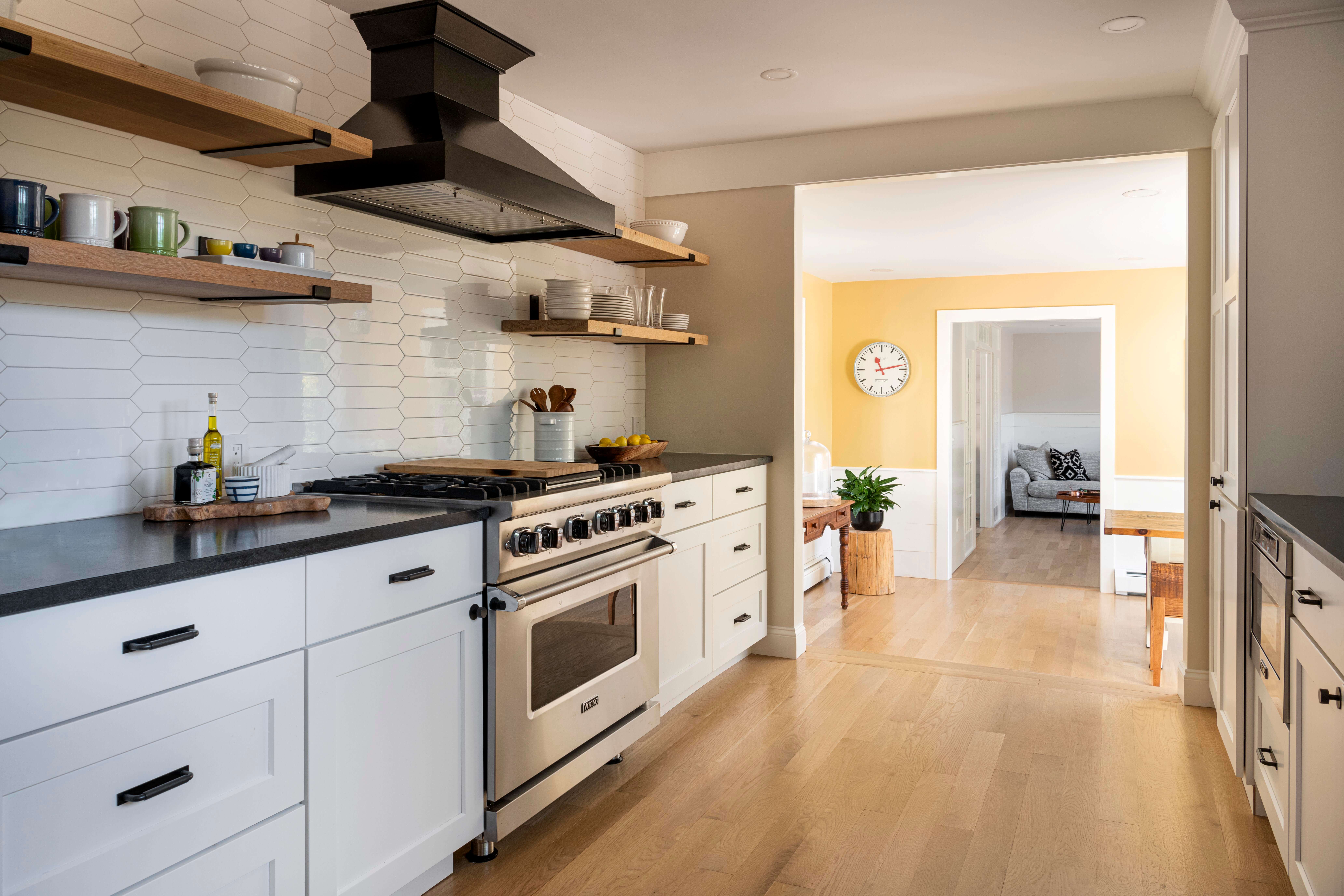black and white kitchen with open shelving, white backsplash and black counters