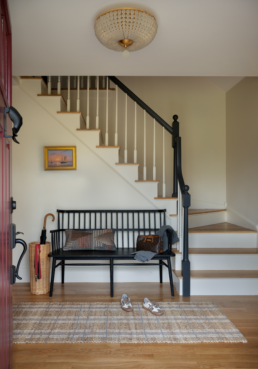 Entry hall with a staircase, iron bench and a framed picture