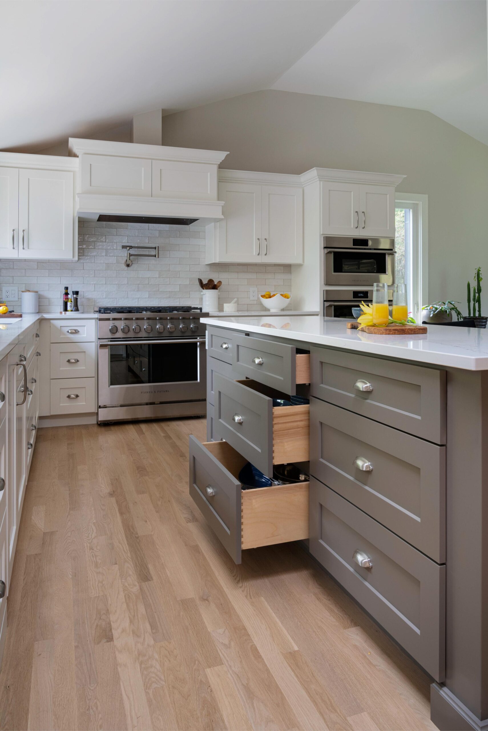 Kitchen with white cabinets and a huge cooking range. The middle island has additional gray cabinets for more storage.