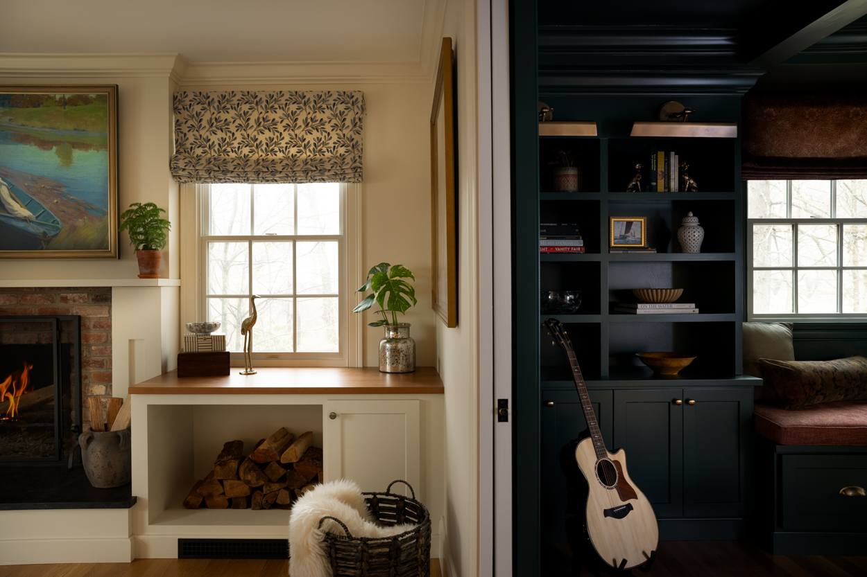 Room with dark built in shelving, a guitar on a stand and a window seat