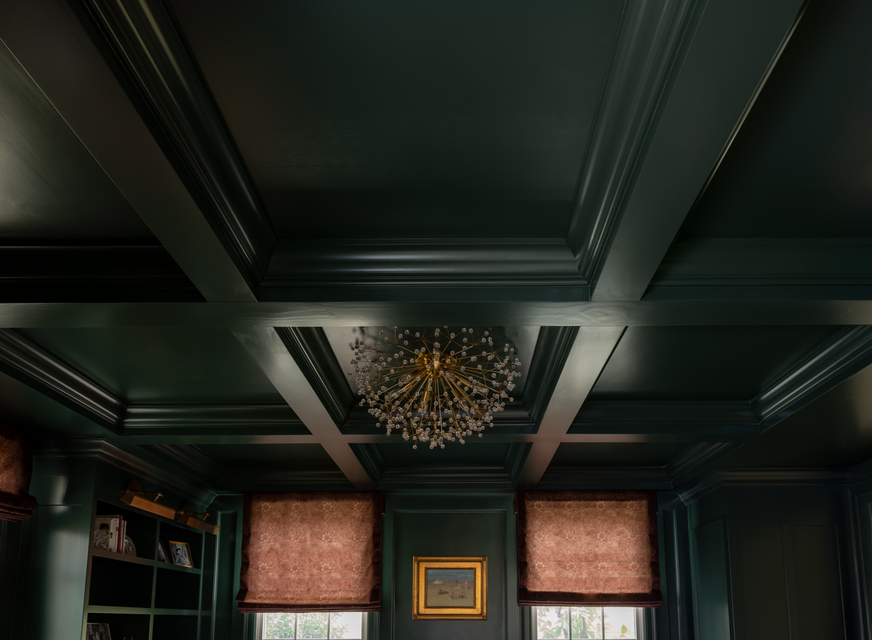 Detail of a coffered ceiling with a brass light fixture in a green room