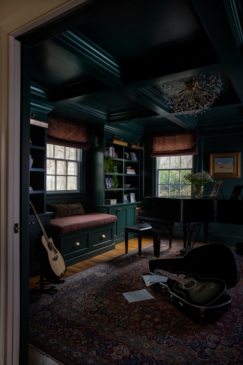 Dark green music room with a coffered ceiling and built in cabinetry