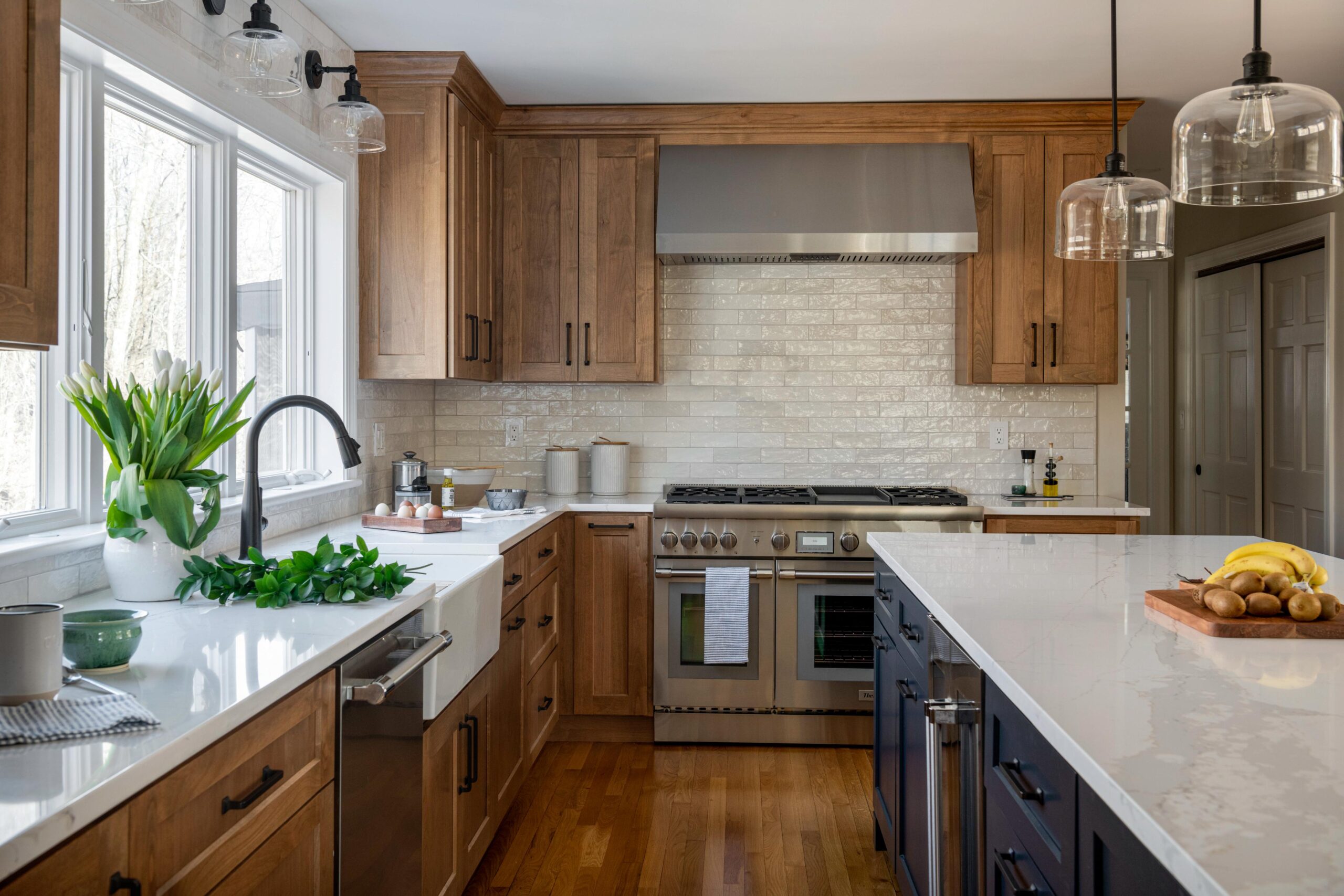 Kitchen with a wooden style cabinet , white countertop, and a farmhouse sink. The center island has dark blue cabinets.