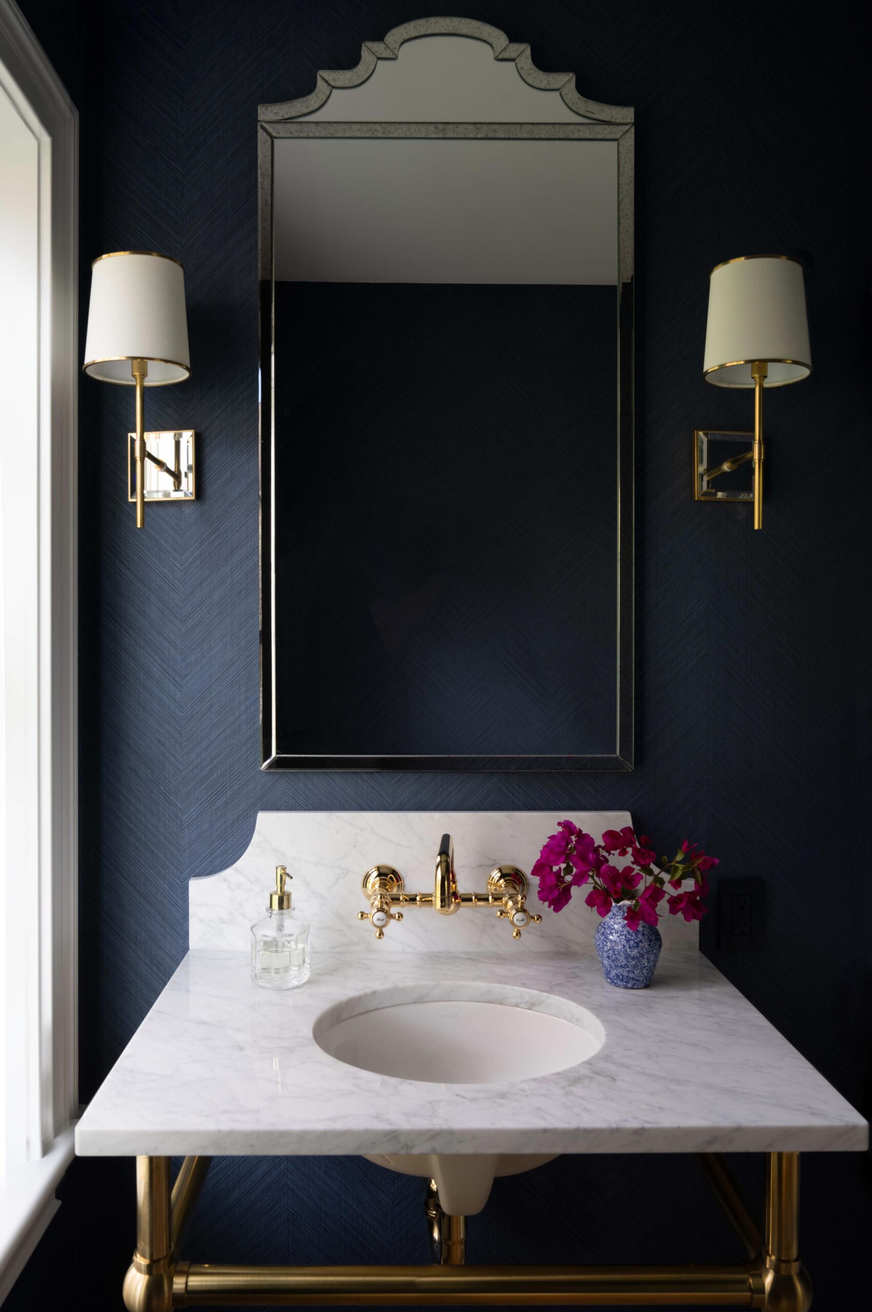 Powder room with navy walls, a marble console sink and a black framed mirror